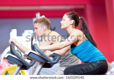 Group of two people in the gym, exercising their legs doing cardio cycling training