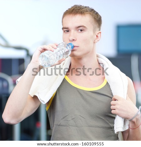 Young man drinking water after sports. Fitness gym.