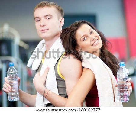 Man and woman drinking water after sport exercises. Fitness gym.