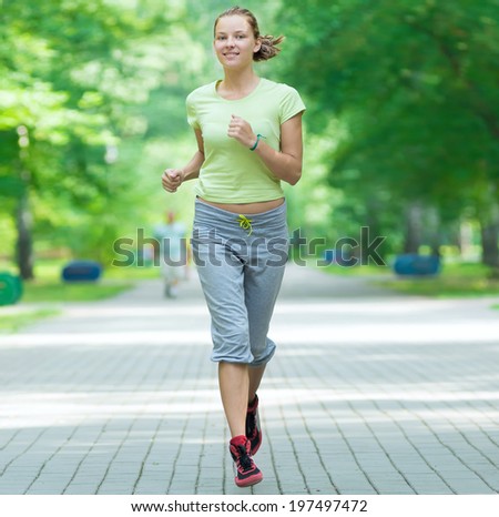Running woman jogging in city street park at beautiful summer morning. Sport fitness model caucasian ethnicity training outdoor.