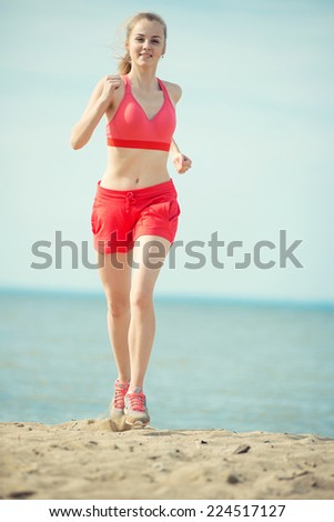 Young lady running. Woman runner running at the sunny summer sand beach. Workout near ocean sea coast. Beautiful fit girl. Fitness model caucasian ethnicity outdoors. Weight loss exercise. Jogging.