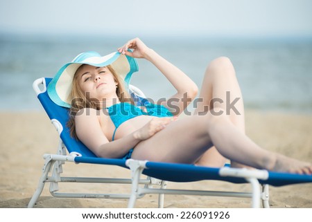 Young lady sunbathing on a beach. sand beach. Outdoor summer portrait of pretty sport style woman in blue bikini. Ocean sea coast. Beautiful fit tan girl. Sexy slim model caucasian ethnicity outdoors.