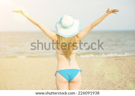 Young lady sunbathing on a beach. Beautiful woman posing at the summer sand beach. Outdoor summer portrait of pretty sport style woman in blue bikini. Slim model caucasian ethnicity outdoors.
