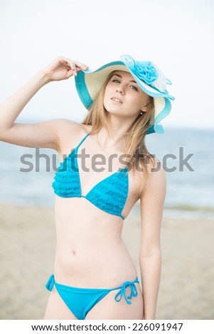 Beautiful woman posing at the summer sand beach. Outdoor summer portrait of pretty sport style woman in blue bikini. Ocean coast. Beautiful fit tan girl. Sexy slim model caucasian ethnicity outdoors.
