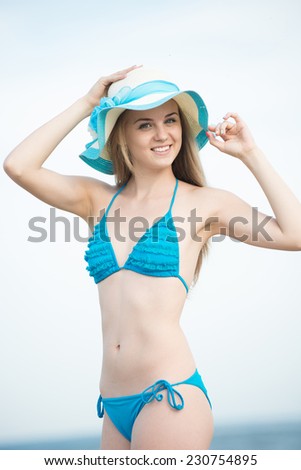 Young lady sunbathing on a beach. Beautiful woman posing at the summer sand beach. Outdoor summer portrait of pretty sport style woman in blue bikini. Ocean sea coast. Beautiful fit tan girl.