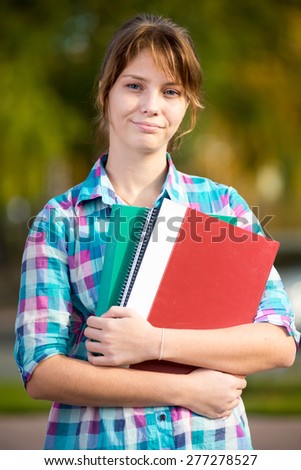 Portrait of young alluring woman holding education books. Standing at summer college park. Student girl.