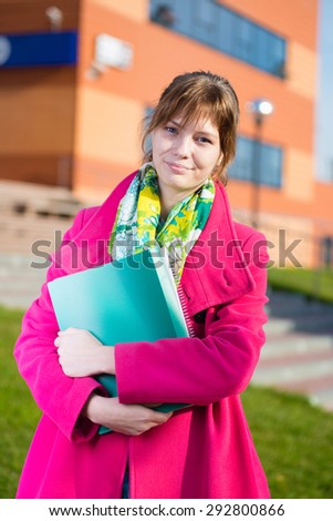 Portrait of young alluring woman holding education books. Standing at summer college park. Student girl.