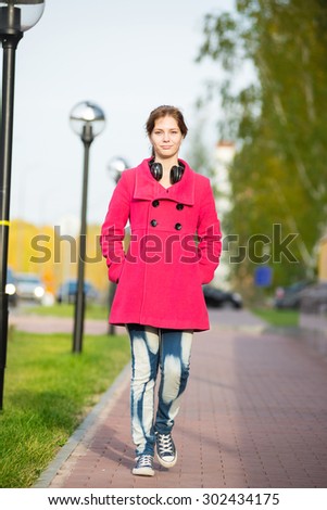Beautiful woman in red coat walking autumn street. Girl walking on a beautiful fall day.
