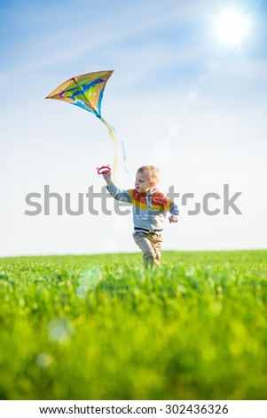 Young boy flies his kite in an open field. Little kid playing with kite on green meadow. Childhood concept.