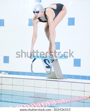 Portrait of a female swimmer, that wearing a swimming cap and goggles and preparing to jump into swimming pool. Sporty woman.