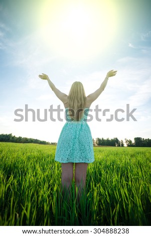 Happiness woman stay outdoor under sunlight of sunset. With raised hands at the sunrise time