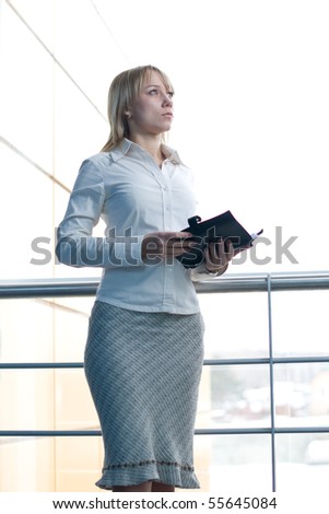 Attractive young businesswoman with day planner in office lobby