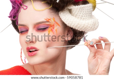 Closeup portrait of beautiful fashion woman with color face art. All in knitting style. Wool balls. Pain.