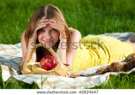 Beautiful young woman on picnic with basket of fruits