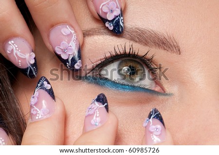 Closeup eyes make-up zone. Nail art. Finger.  Pink and blue color. High resolution.