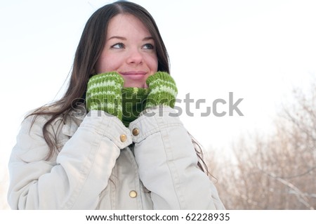 Winter lifestyle. Beautiful girl with green scarf and gloves over snow landscape