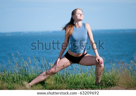 Beautiful teenage sport woman   doing stretching exercise over blue sea landscape. Yoga
