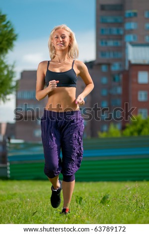 Beautiful young woman running over green city street landscape