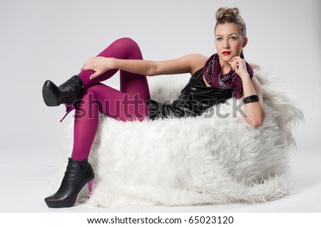 Beautiful young rock girl in purple stocking sitting on white fur sofa