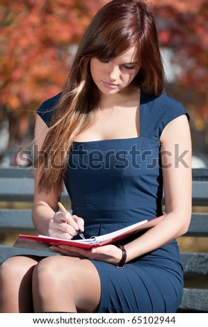 Young business woman planing, writing and reviewing  diary at city park. Student