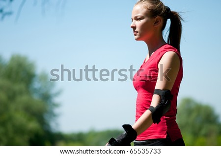 Beautiful young woman rink on roller-skate in green park on sunny summer day