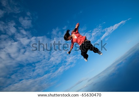 Beautiful sport woman in urban sportswear jumping and fly over blue sky with clouds