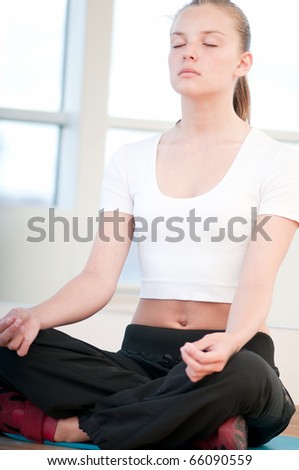 Young woman doing yoga exercises on floor at the sport gym