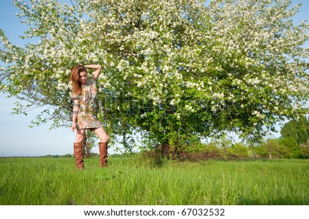 Beautiful young fashion woman in color dress posing outdoor in garden