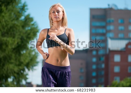 Beautiful young woman running over green city street landscape