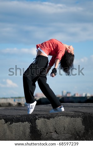 Beautiful woman dancing hip-hop modern style over urban city landscape and blue sky