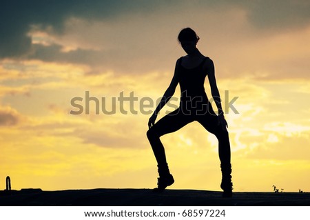 Silhouette photo of dancing woman in modern pilates style over sunset landscape. Yoga