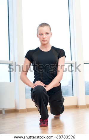Young woman doing stretching exercises on the floor at the sport gym