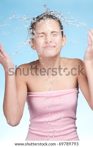 Closeup portrait of young beautiful girl in bath that washing face in cold fresh water. Splash!
