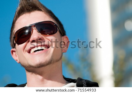 Close up of young casual cheerful man walking in city park