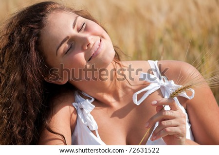 Beautiful woman with perfect hair and skin posing in wheat field on sunny summer day. Picnic.