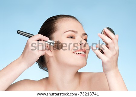 Beautiful young adult woman applying cosmetic paint brush - close-up portrait of cheek zone