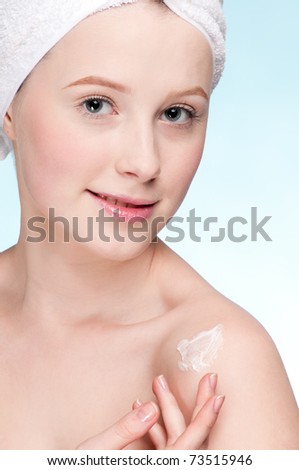 Beautiful woman applying moisturizer cream on face. Close-up fresh young woman face