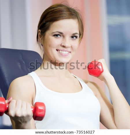 Beautiful sport woman doing power fitness exercise at sport gym. Dumbbell weight!