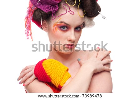 Closeup portrait of beautiful fashion woman with color face art. All in knitting style. Wool balls.