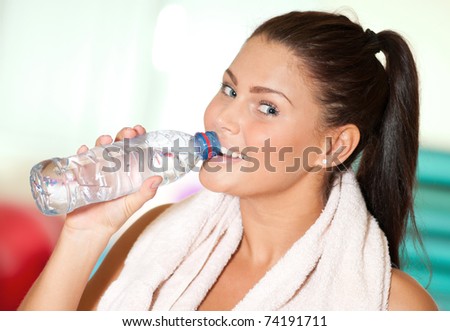 Beautiful sport woman with towel drink cold fresh mineral water after sport train. Thirst!
