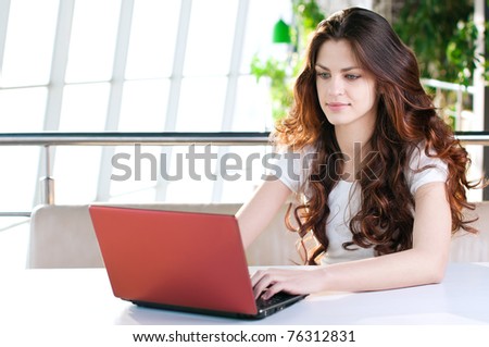 A young attractive business woman sitting in a cafe with a laptop