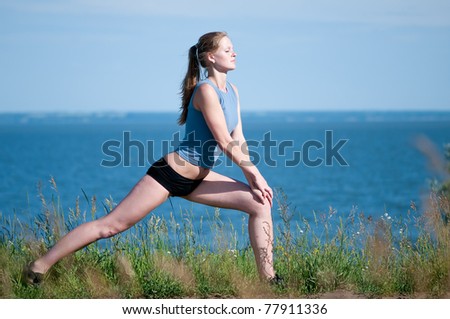 Beautiful teenage sport woman   doing stretching exercise over blue sea landscape. Yoga