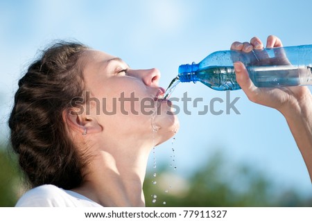 Beautiful young woman drinking water after exercise on sunny summer day. Thirst