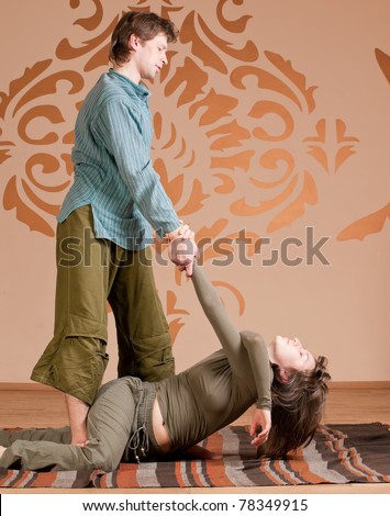 Two young man and woman couple doing yoga. Massage