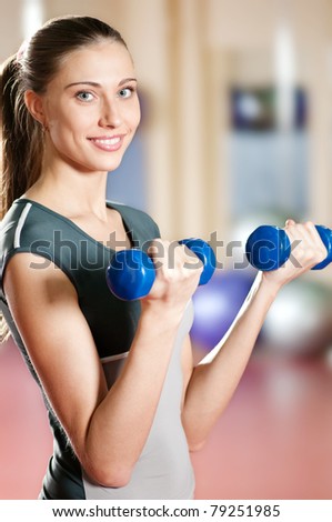 Beautiful sport woman doing power fitness exercise at sport gym. Dumbbell