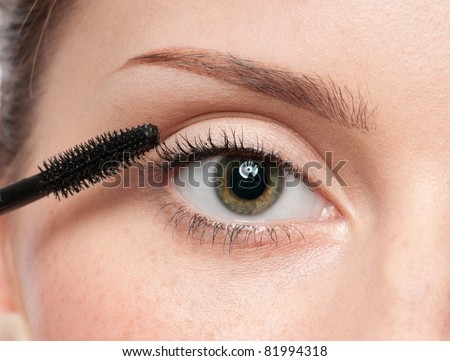 Beautiful woman applying mascara on her eyelashes - isolated on white
