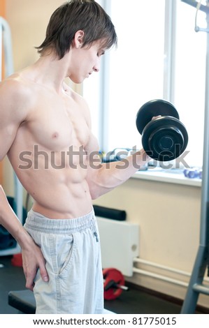 Fitness - powerful muscular man lifting weights in gym club