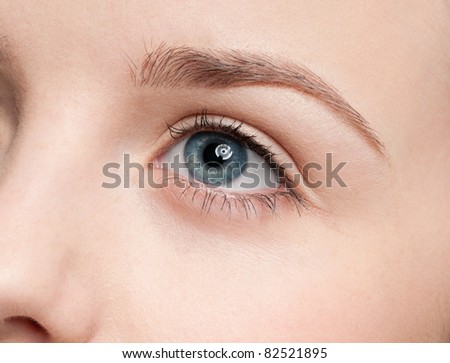 Beautiful young woman applying cosmetic paint brush - close-up portrait of eye shadow zone