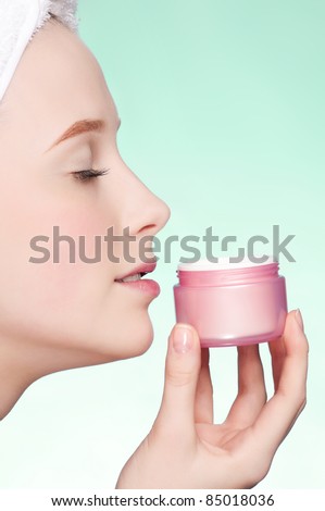 Beautiful woman tender jar of moisturizer cream. Close-up fresh young woman face