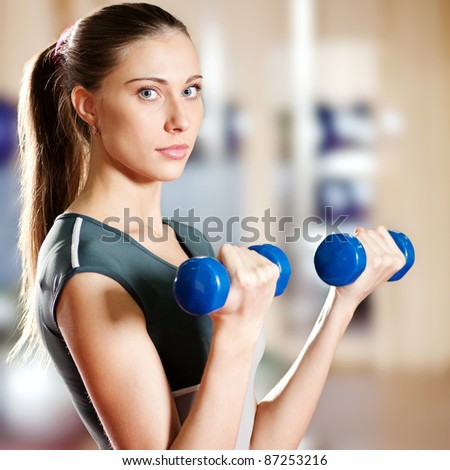 Beautiful sport woman doing power fitness exercise at sport gym. Dumbbell